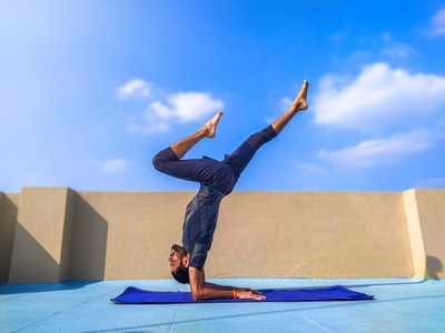 Dressed in black trousers and shirt man standing yoga mat in blue
